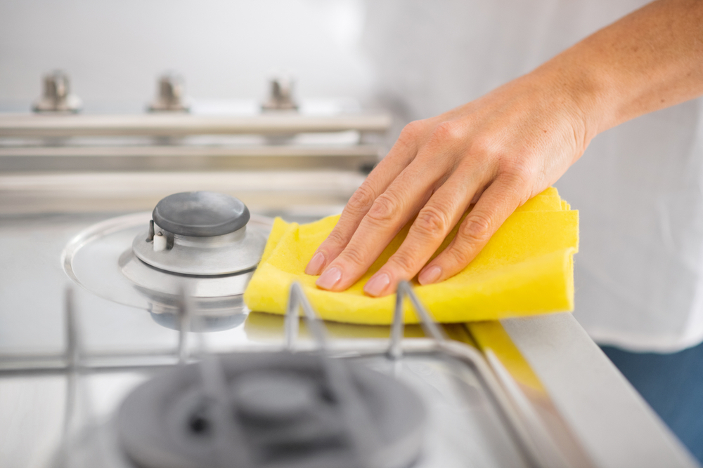 limpiando estufa de cocina con paño amarillo